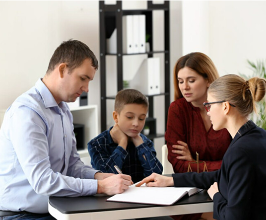 A family sits with an advisor at a table, reviewing documents. The scene appears focused and serious, highlighting cooperation and decision-making.